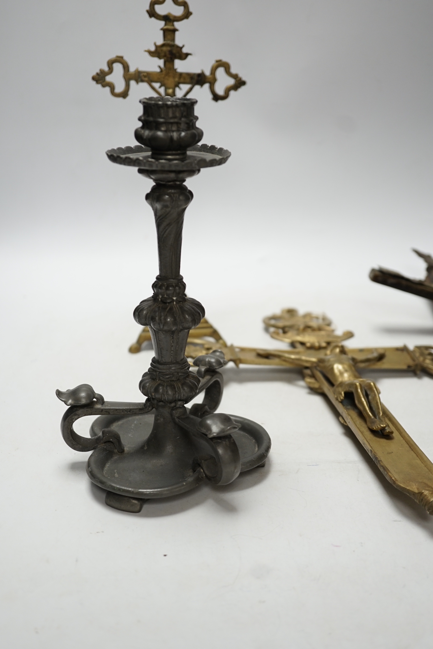 Three brass crucifixes and an Orivit pewter candlestick, tallest 45cm high